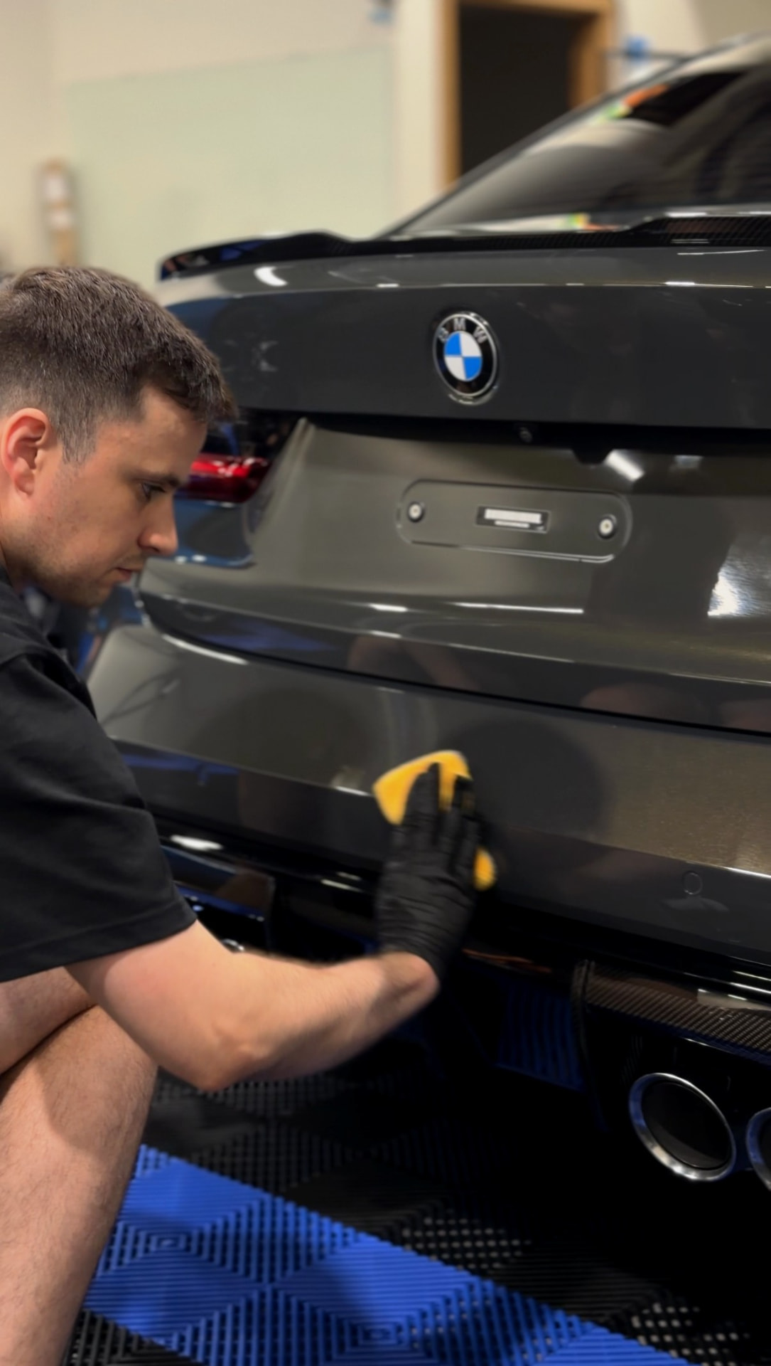 Technician wiping down the rear of a grey BMW after ceramic coating